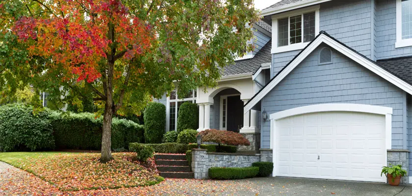 A summer home with a tree just starting to turn for the autumn seasons.