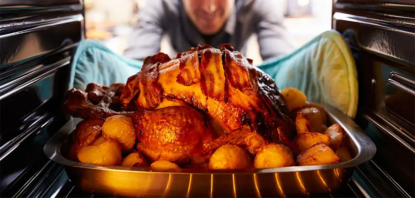 A man cooking a turkey in a clean oven.