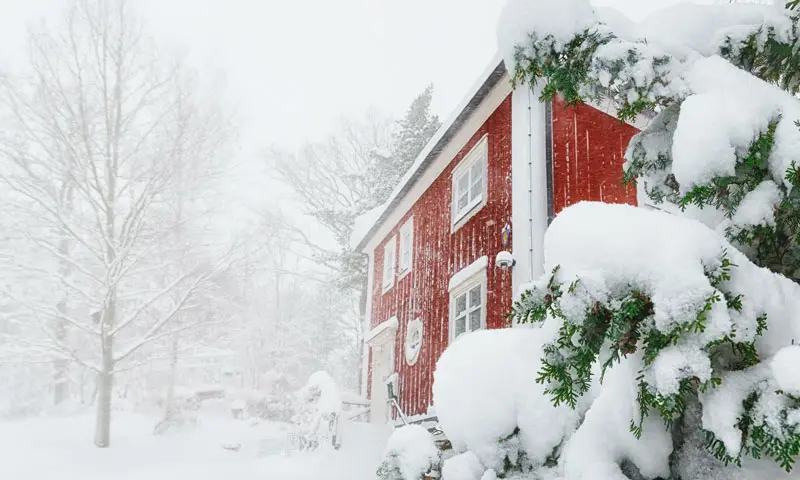 A rural red home in the middle of a snow storm.