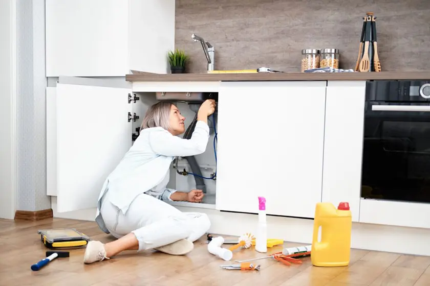 Woman Fixing Kitchen Sink - DIY Home Repairs