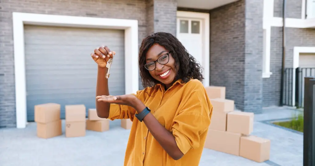 Excited woman holding key to her new home, having completed the home buying process.