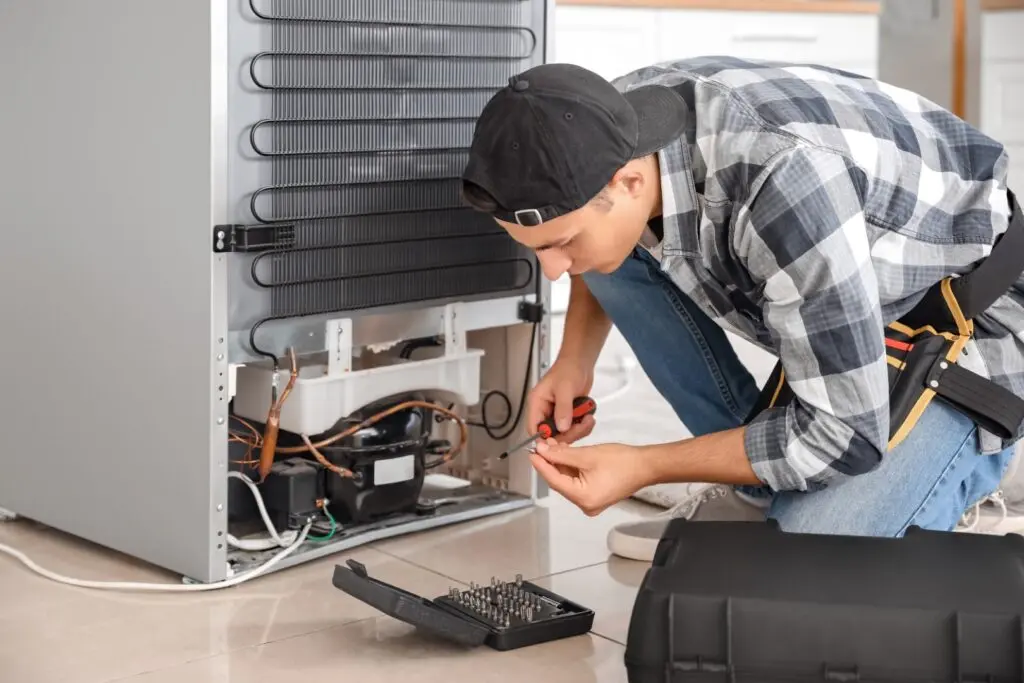 Service technician fixing broken refrigerator.