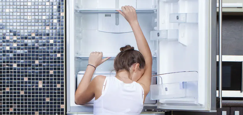 woman crying over broken fridge